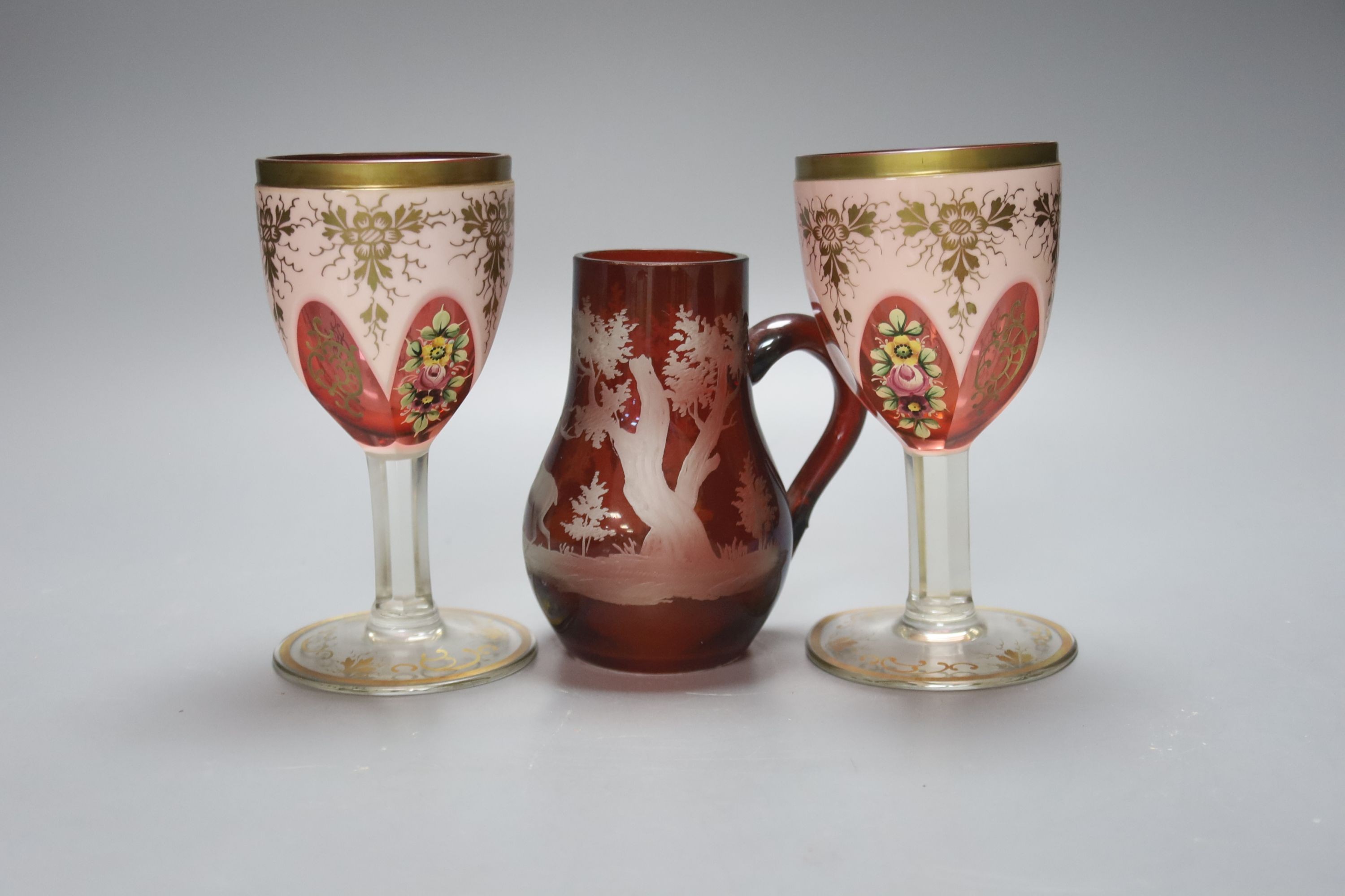 A pair of Bohemian overlaid glass goblets and a wheel engraved ruby glass jug (3) 15cm